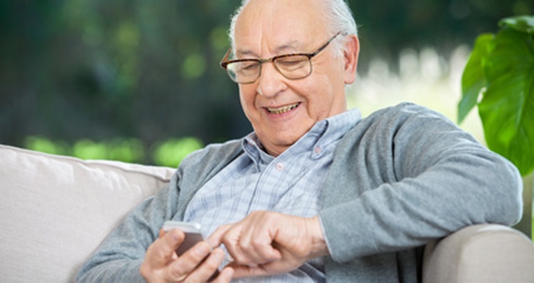 Smiling Senior Man Text Messaging Through Mobilephone